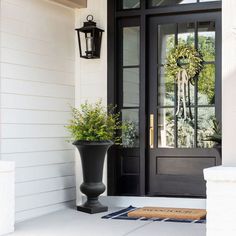 a black front door with two planters on the porch