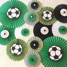 green and black paper fans with soccer balls on them are arranged against a white wall