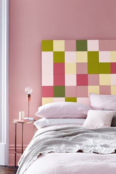 a bed with pink and green squares on the headboard