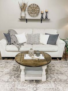 a living room with a couch, coffee table and two vases on the wall