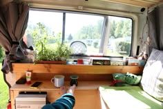 the interior of a camper van with plants and books on the windows sill