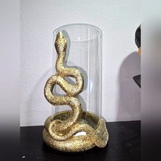 a gold snake in a glass vase on a table