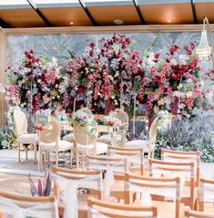 a room filled with lots of white chairs and tables covered in floral arrangements on the wall