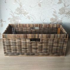 an empty wicker basket sitting on top of a wooden floor next to a wall