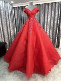 a red ball gown is on display in front of a curtained window with silver sequins