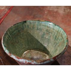 a green bowl sitting on top of a wooden table