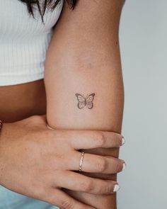 a woman's arm with a small butterfly tattoo on the left side of her body