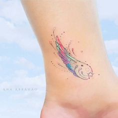 a colorful tattoo on the side of a woman's foot with an angel wing