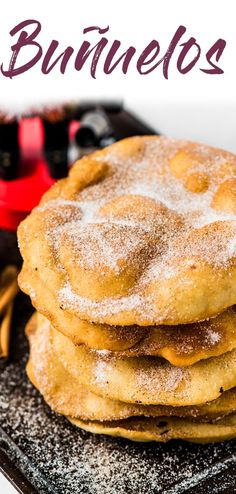 a stack of pancakes sitting on top of a black plate covered in powdered sugar