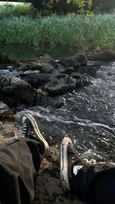 someone's shoes are sitting on the edge of a stream