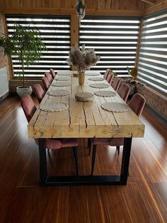 a wooden table sitting on top of a hard wood floor next to a tall plant