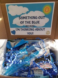 a box filled with blue and white confetti next to a sign that says something out of the blue because i'm thinking about you