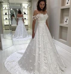 a woman standing in front of a mirror wearing a wedding dress with flowers on it