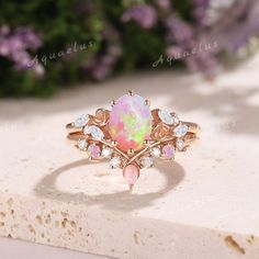 an opal and diamond ring sitting on top of a stone