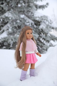 a doll with long hair standing in the snow wearing boots and a pink dress,