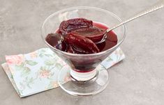 a glass bowl filled with fruit on top of a table next to a napkin and spoon