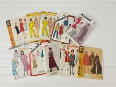 six vintage sewing patterns from the 1950's and 1960s's are laid out on a white surface