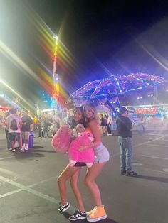 two girls are posing for the camera at an amusement park