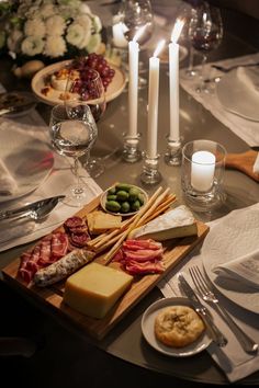 a table topped with plates and glasses filled with food next to candles on top of a table