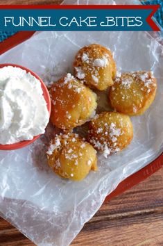 a red plate topped with donuts covered in powdered sugar next to a bowl of whipped cream