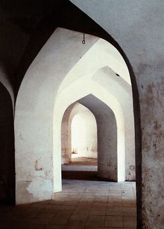 an archway in the middle of a building with tile flooring and walls that have been painted white