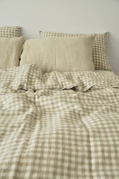 an unmade bed with checkered sheets and pillows