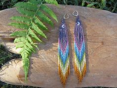 two pairs of multicolored beaded earrings sitting on top of a tree stump