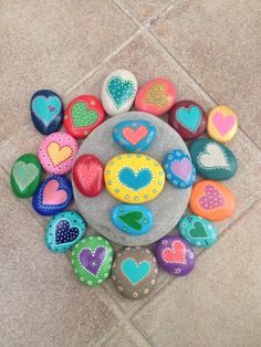 colorful painted rocks arranged in the shape of hearts on a tile floor next to each other