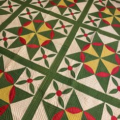 a green and yellow quilt with red, yellow, and green designs on it's sides