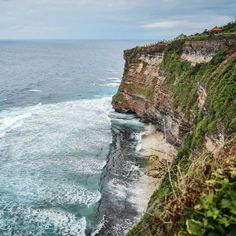 the cliff is next to the ocean with waves coming in