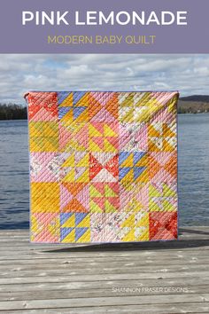 the pink lemonade modern baby quilt is shown on a dock