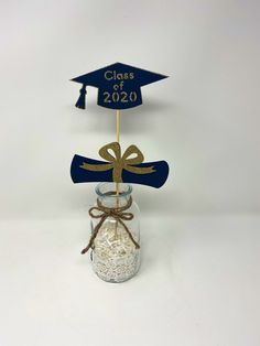 a graduation decoration in a mason jar with a graduate's cap and diploma on top