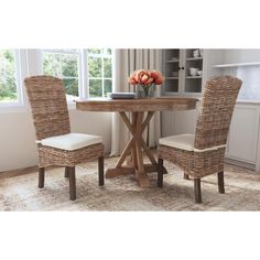 a round table with two chairs and a vase on it in front of a window