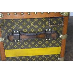 an old louis vuitton trunk with yellow stripes and rivets on it