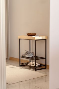 a wooden table sitting in the corner of a room next to a wall with shoes on it