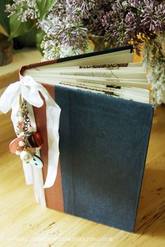 an open book sitting on top of a wooden table next to some purple and white flowers