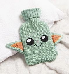 a green knitted baby yoda toy laying on top of a white blanket