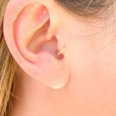 a woman's ear is shown with a single gold ring on the end of it