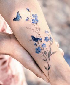 a woman's arm with blue flowers and butterflies on it