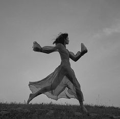 a woman in a long dress running across a field