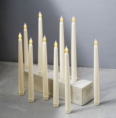 a group of white candles sitting on top of a block of concrete next to each other