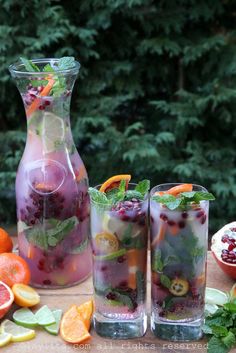 three glasses filled with liquid and fruit on a table next to some oranges, limes, and other fruits