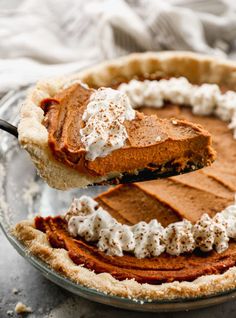 a piece of pie is being lifted from the pie dish with a fork and whipped cream on top