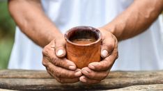 a person holding a wooden cup in their hands