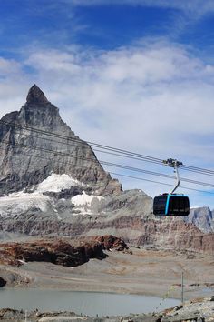 a ski lift going up the side of a mountain with snow covered mountains in the background