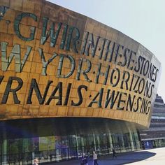 people walking in front of a building that has words on the outside and inside it