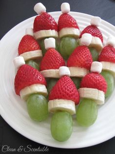 some fruit is arranged in the shape of santa's hats on a white plate