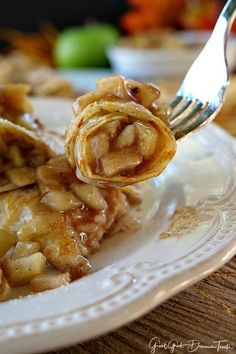 a white plate topped with pancakes covered in caramel sauce and apple slices next to a fork