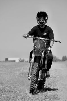 a man riding on the back of a dirt bike in a field with tall grass