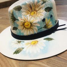 a hat with flowers painted on it sitting on top of a wooden floor